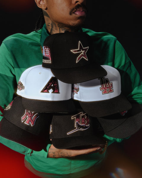 NEW ERA 5950 MAGMA COLLECTION HERO IMAGE-MAN HOLDING BLACK AND WHITE FITTED HATS WITH PINK LOGOS-HOUSTON ASTROS,ARIZONA DIAMONDBACKS,LOS ANGELES DODGERS,NEW YORK YANKEES,TAMPA BAY RAYS,SEATTLE MARINERS