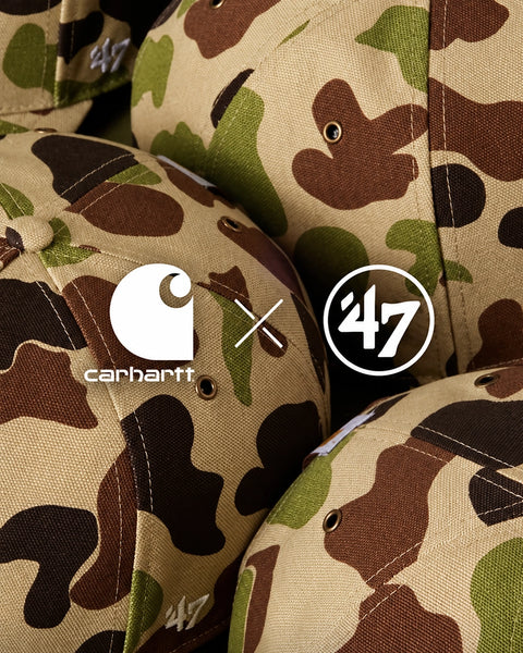 Close-up of multiple camouflage baseball caps in a tan, brown, olive green, and black camo pattern, with Carhartt and '47 logos overlaid in the center.